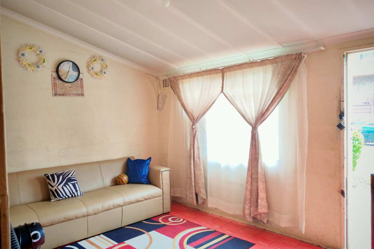 A living room featuring a large window with curtains, tiled flooring, and direct access to the exterior.