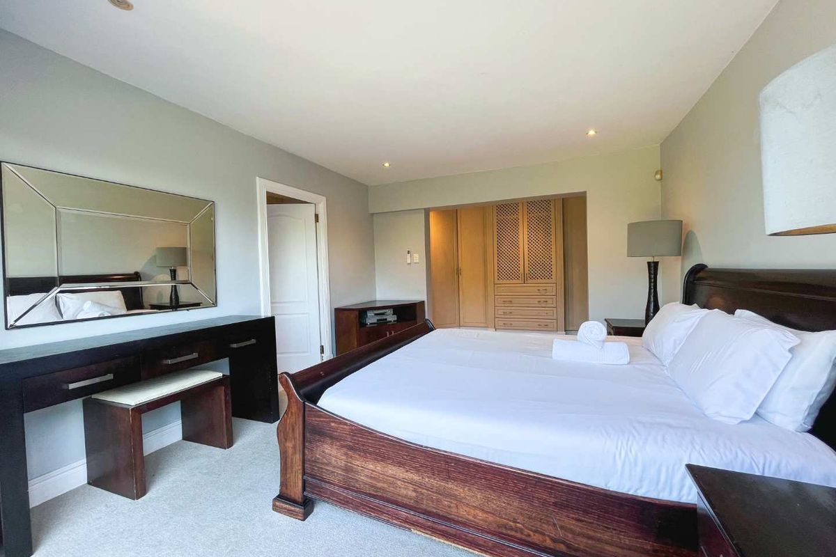 Spacious bedroom featuring neutral wall tones, plush carpeting, and extensive built-in wooden cabinetry for ample storage.
