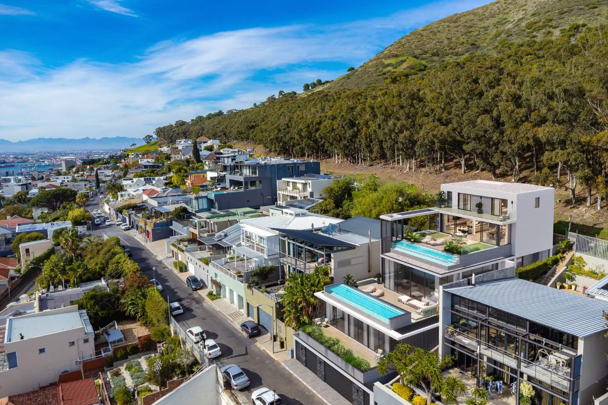 Aerial view of a modern multi-level apartment complex featuring rooftop swimming pools, expansive balconies, and contemporary architectural design in a hillside setting.