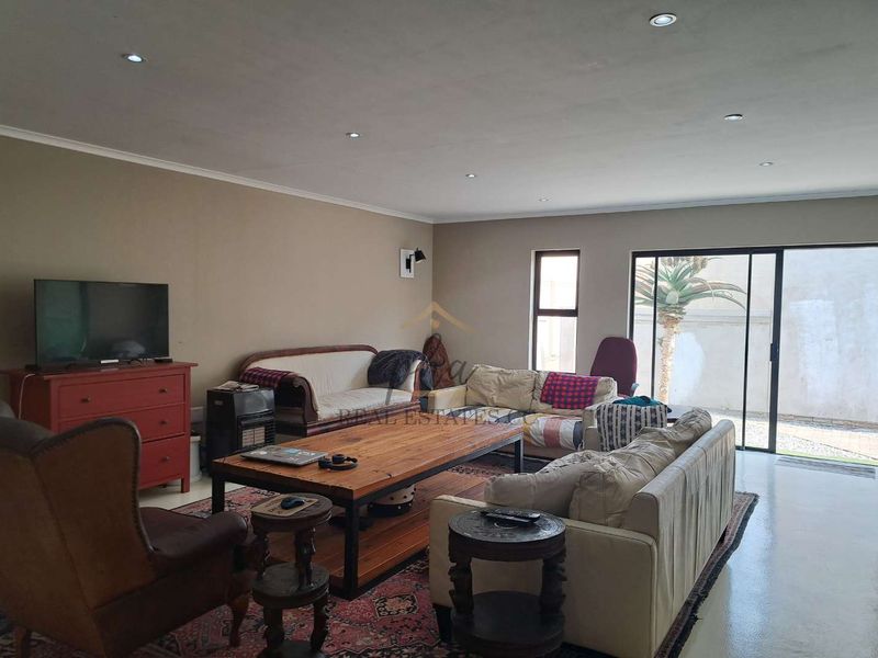 Spacious living room featuring polished concrete floors, recessed downlighting, and large sliding glass doors providing access to the outdoor area.