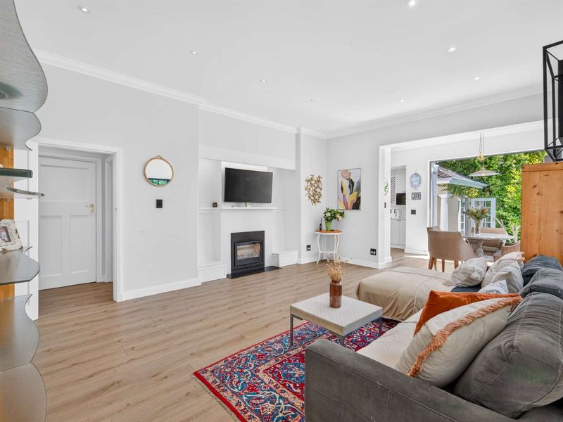 Spacious open-plan living area featuring modern laminate flooring, a built-in fireplace, and seamless flow to an outdoor patio space.