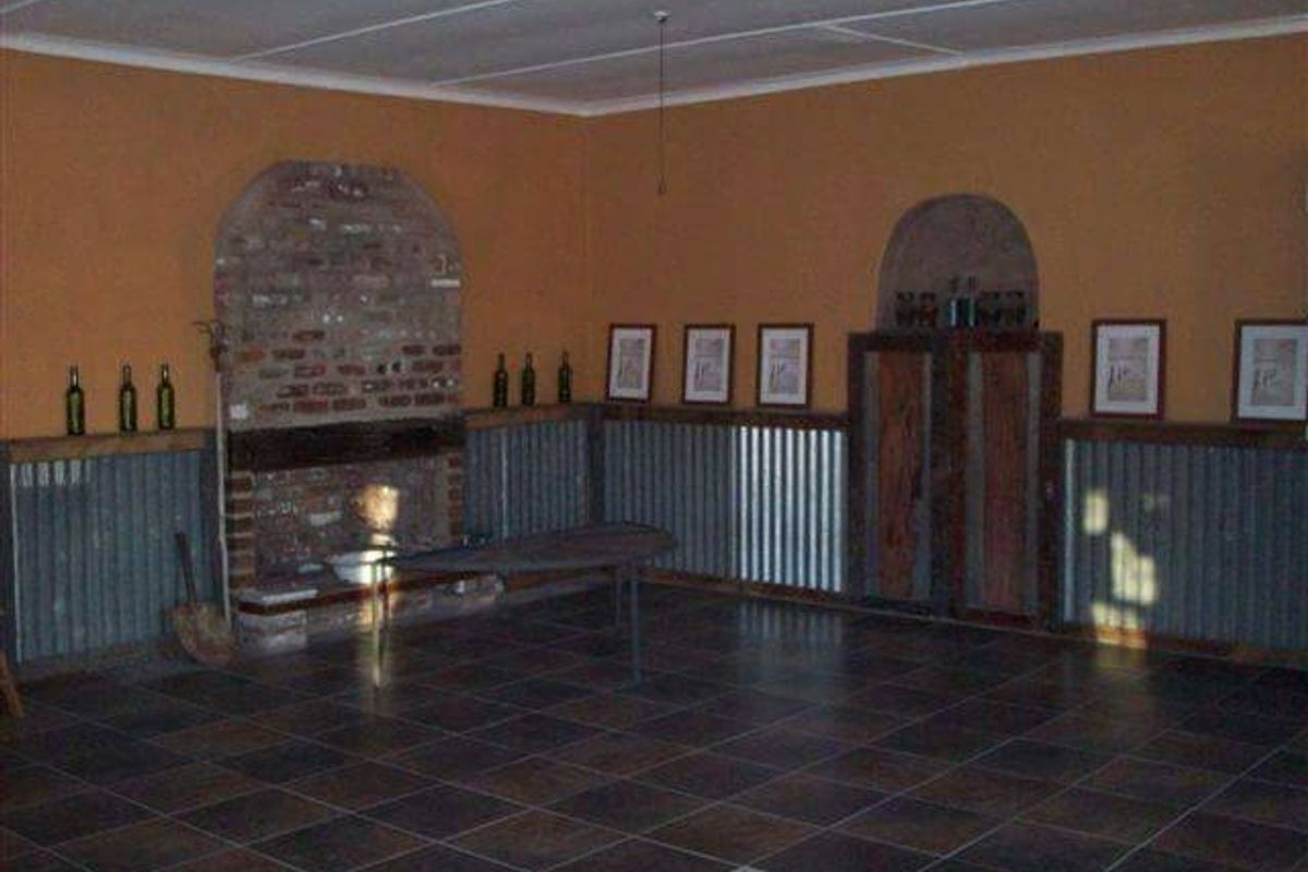 Spacious living area featuring a rustic brick fireplace, corrugated metal wall paneling, and dark ceramic floor tiles.