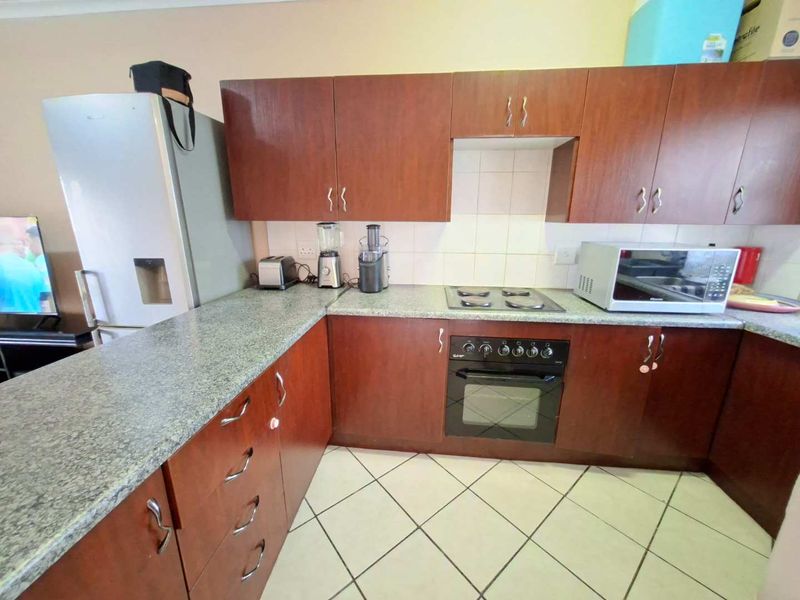 Functional kitchen featuring dark wood-look cabinetry, granite countertops, tiled backsplash, and built-in oven with electric hob.