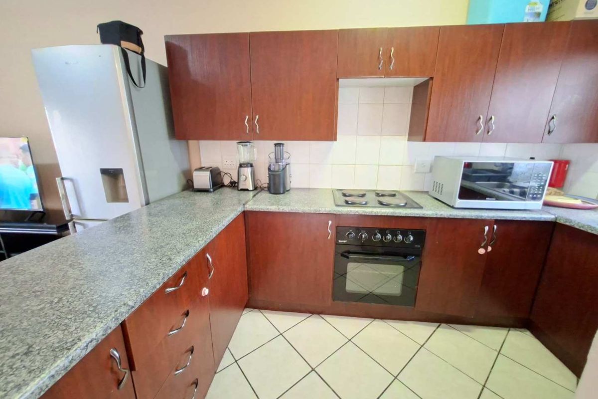 Functional kitchen featuring dark wood-look cabinetry, granite countertops, tiled backsplash, and built-in oven with electric hob.