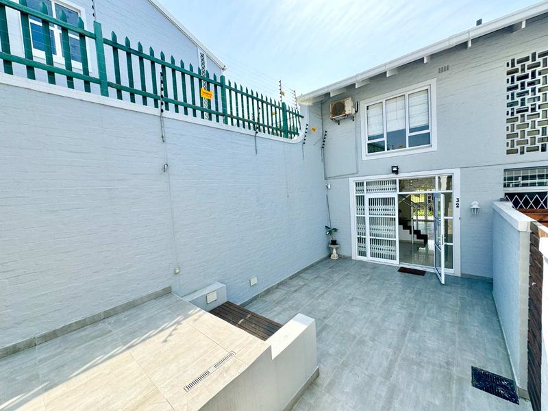 A well-maintained front entrance area featuring tiled flooring, secure gated access, and perimeter electric fencing for added security.