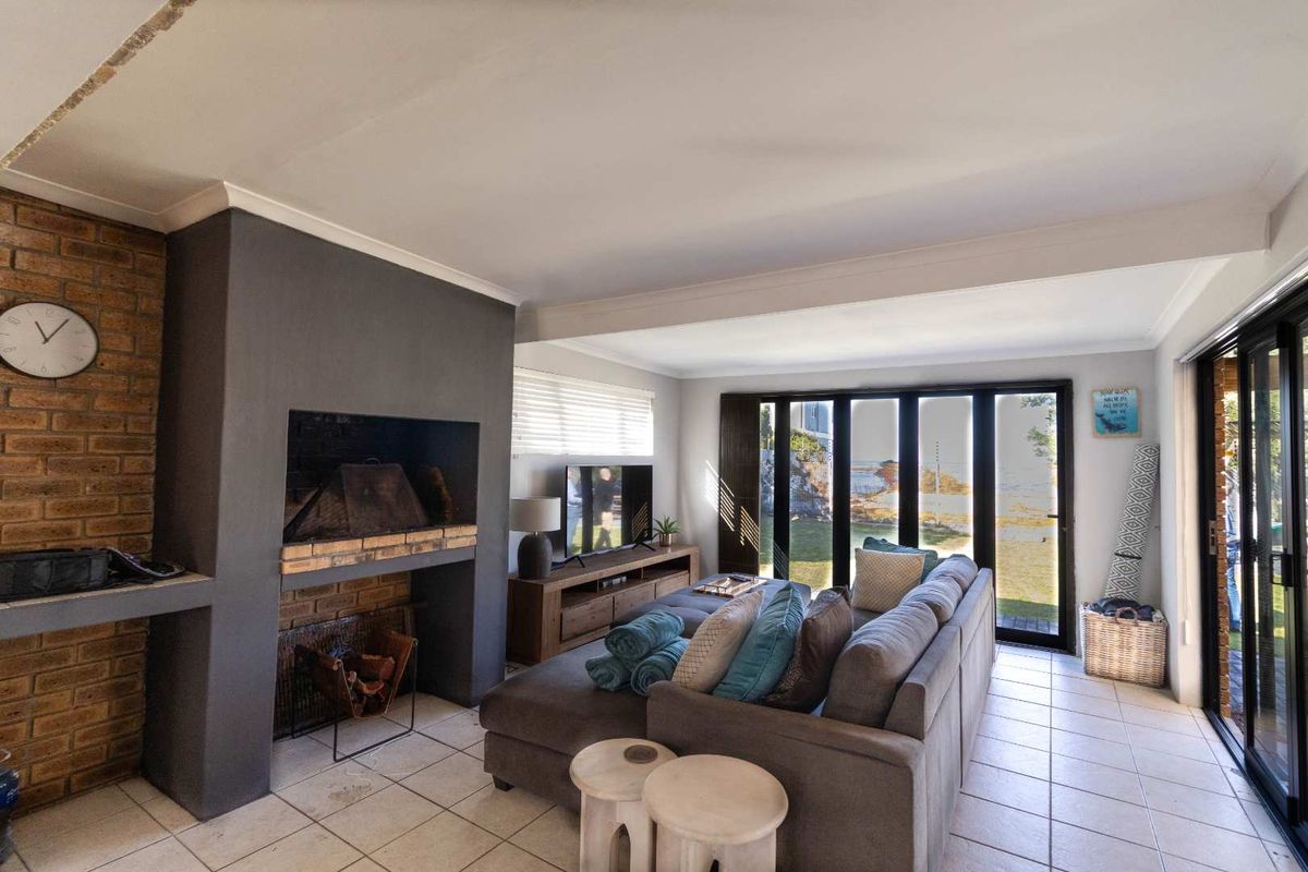 Spacious living room featuring a built-in brick fireplace, tiled flooring, and large glass sliding doors providing natural light and garden access.