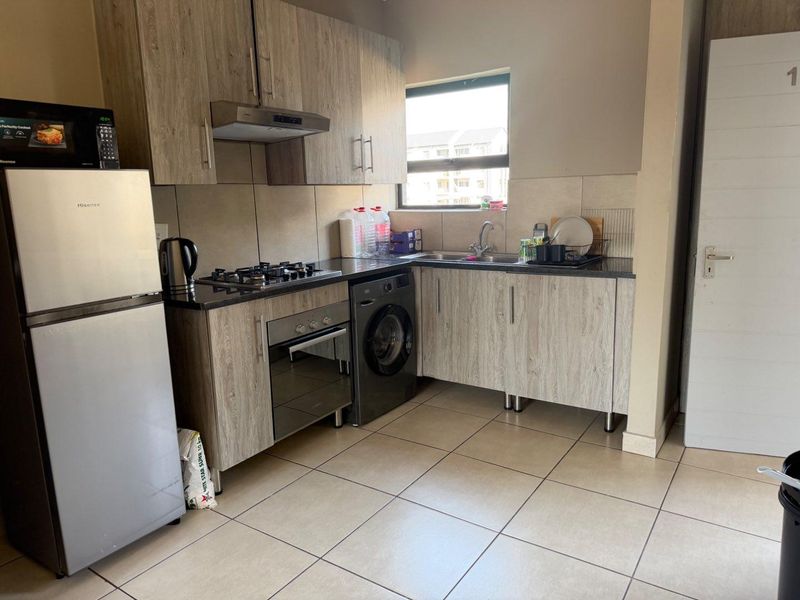 Compact kitchen featuring modern wood-look cabinetry, granite countertops, a gas hob, built-in oven, and integrated space for a washing machine.