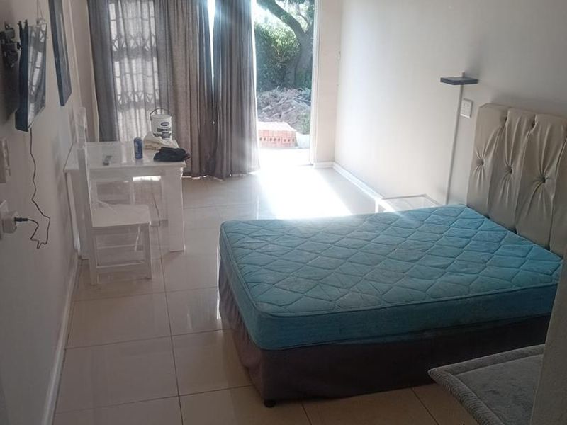 A bedroom featuring tiled flooring, a ceiling fan, and a sliding glass door providing access to an outdoor area.