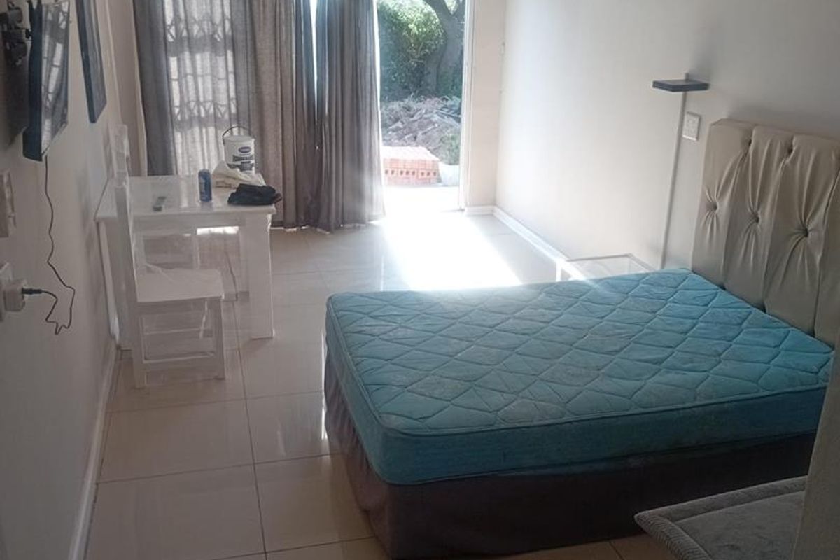 A bedroom featuring tiled flooring, a ceiling fan, and a sliding glass door providing access to an outdoor area.