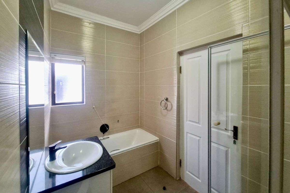 A modern bathroom featuring a built-in bathtub, a vanity with a granite countertop, and a separate shower enclosure with tiled walls.