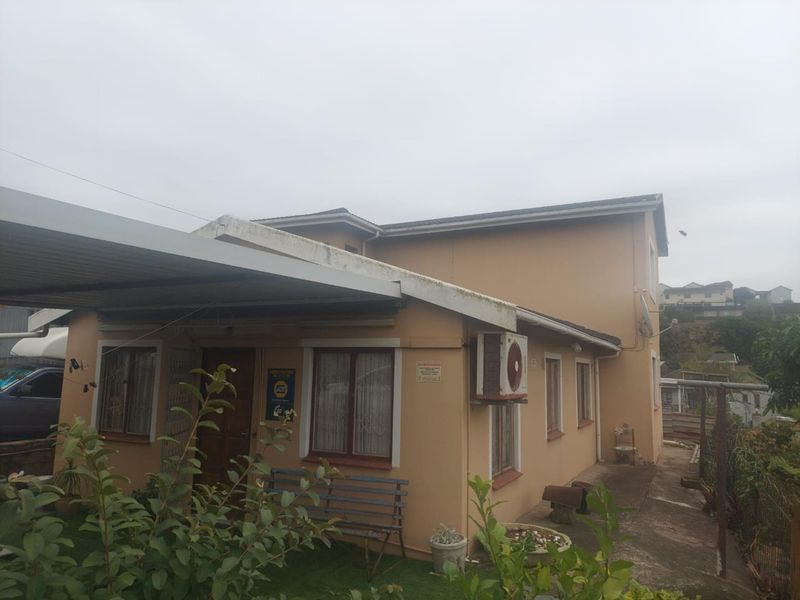 Front exterior view of the house featuring a carport, paved walkway, and wall-mounted air conditioning unit.