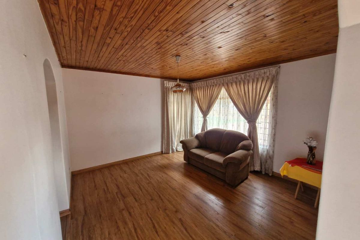 A living room featuring wood-paneled ceilings and wood-look laminate flooring, providing a warm and traditional aesthetic.