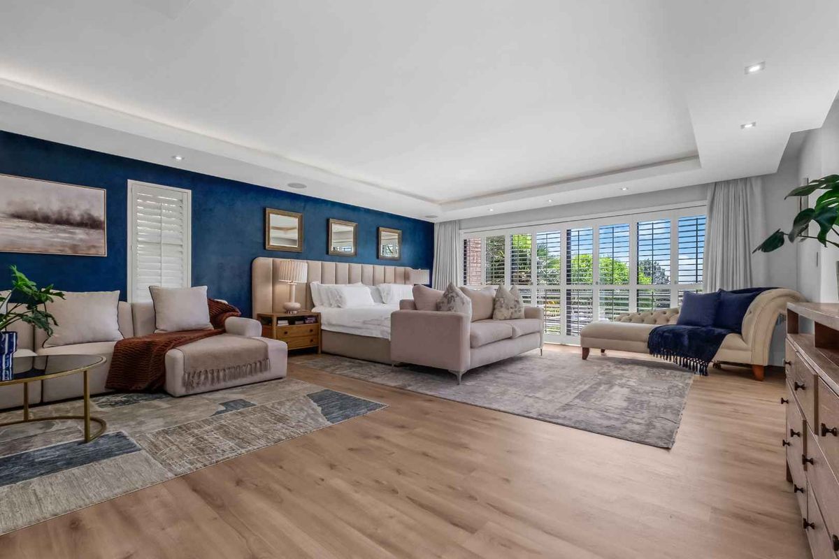 Spacious master bedroom featuring modern laminate flooring, recessed ceiling lighting, and large sliding glass doors with plantation shutters leading to an outdoor area.
