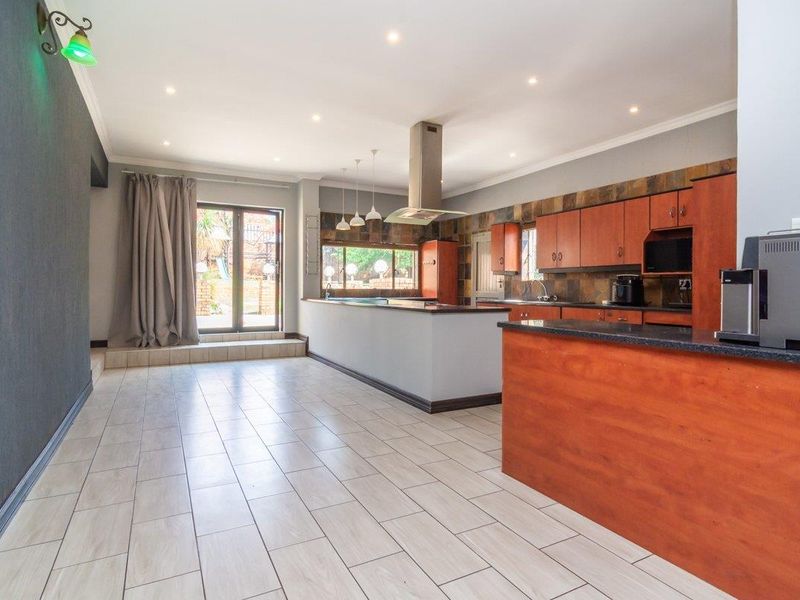 Spacious open-plan kitchen and living area featuring wood-finish cabinetry, granite countertops, tiled flooring, and direct access to the outdoor patio through sliding glass doors.
