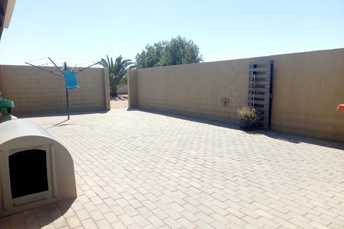 A paved rear courtyard area enclosed by high boundary walls, featuring a built-in pet shelter and open outdoor space.