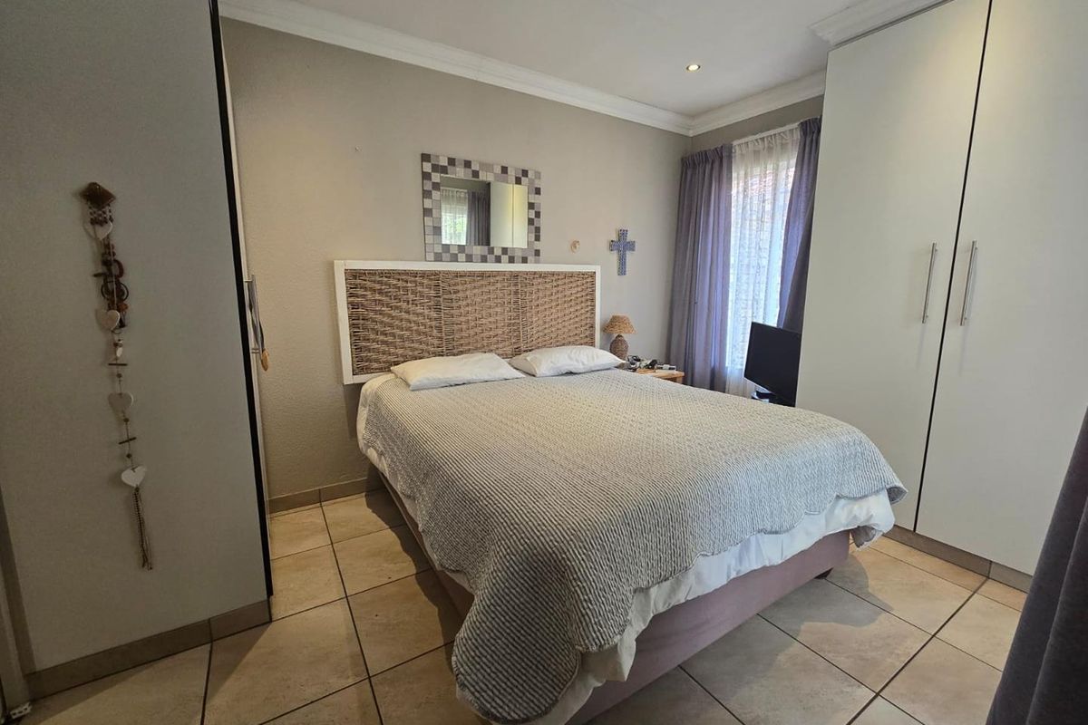 A well-maintained bedroom featuring neutral tiled flooring, built-in cupboards, and recessed downlighting, offering a clean and functional living space.