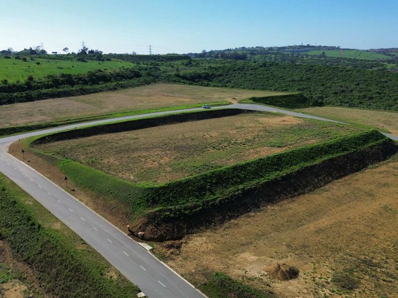 Aerial view of a large, cleared industrial plot featuring an elevated embankment and direct access to a paved road.