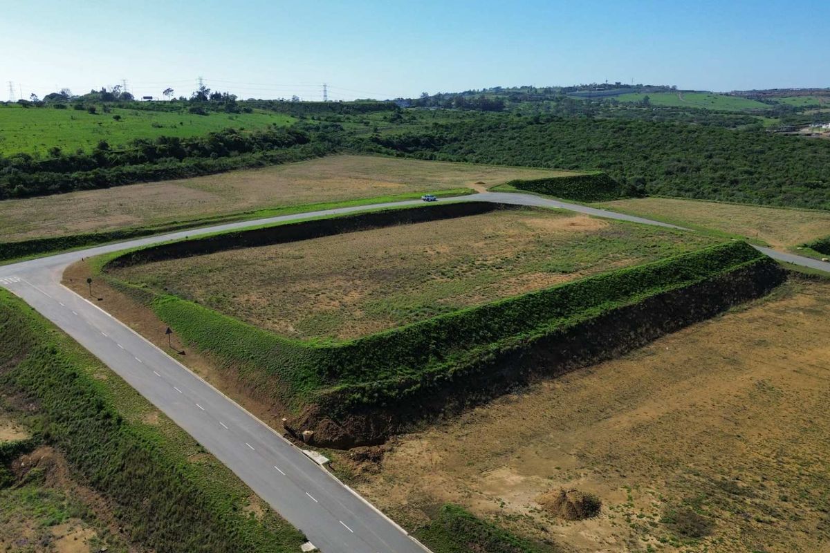 Aerial view of a large, cleared industrial plot featuring an elevated embankment and direct access to a paved road.