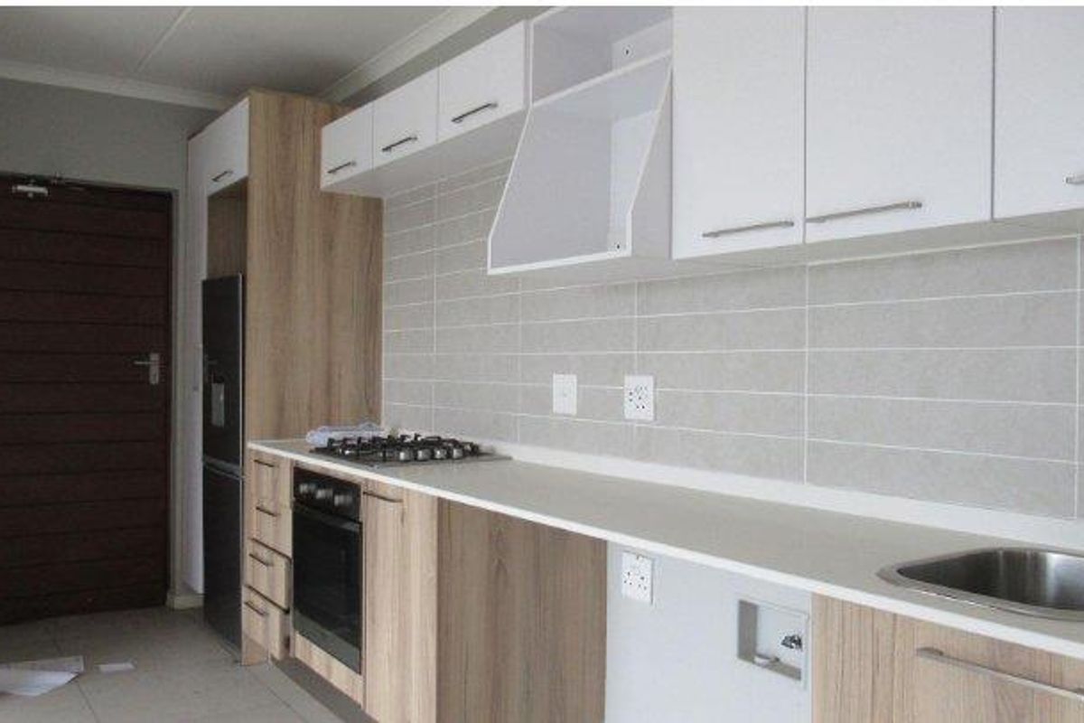 Modern kitchen featuring light wood-tone and white cabinetry, gas hob, built-in oven, tiled backsplash, and integrated plumbing for appliances.