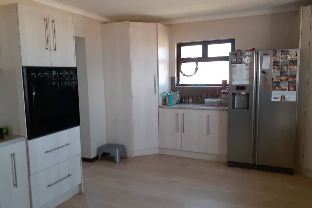 A functional kitchen featuring light-toned cabinetry, built-in oven, and space for a large refrigerator, finished with light wood-look flooring.