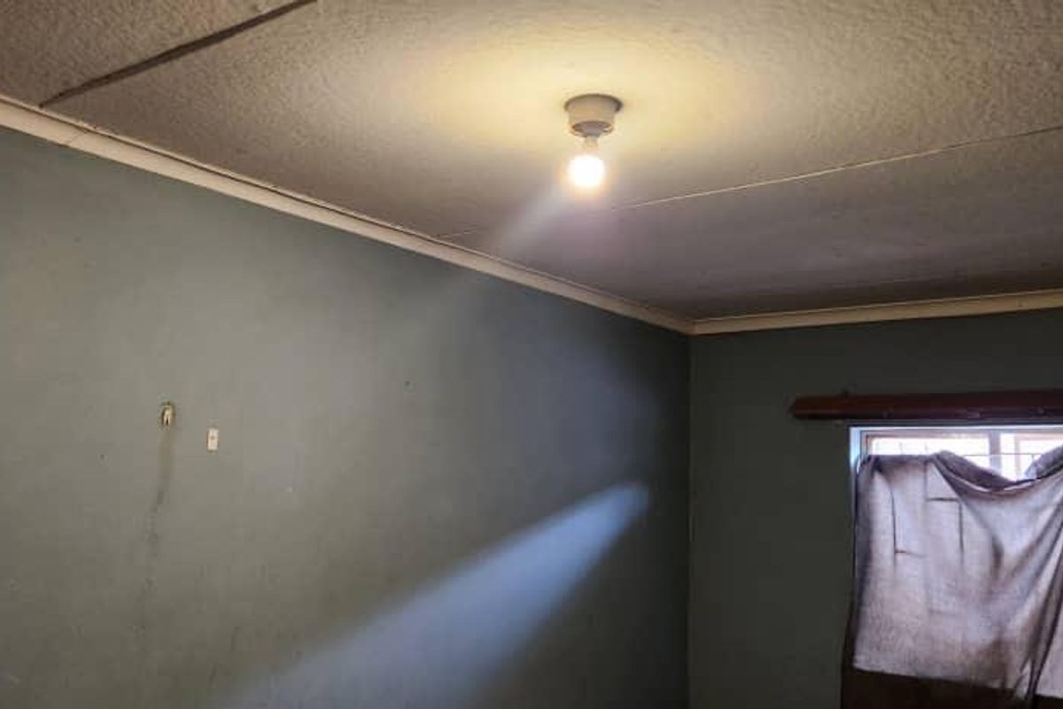 A vacant bedroom featuring a textured ceiling with visible cracks and walls requiring cosmetic attention and repainting.