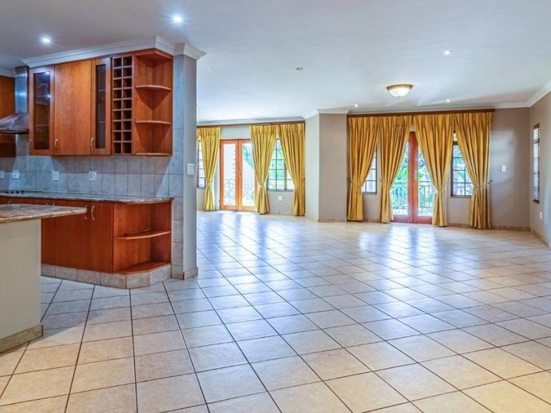 Spacious open-plan living area featuring a functional kitchen with wooden cabinetry, granite countertops, and direct access to the outdoor space through french doors.