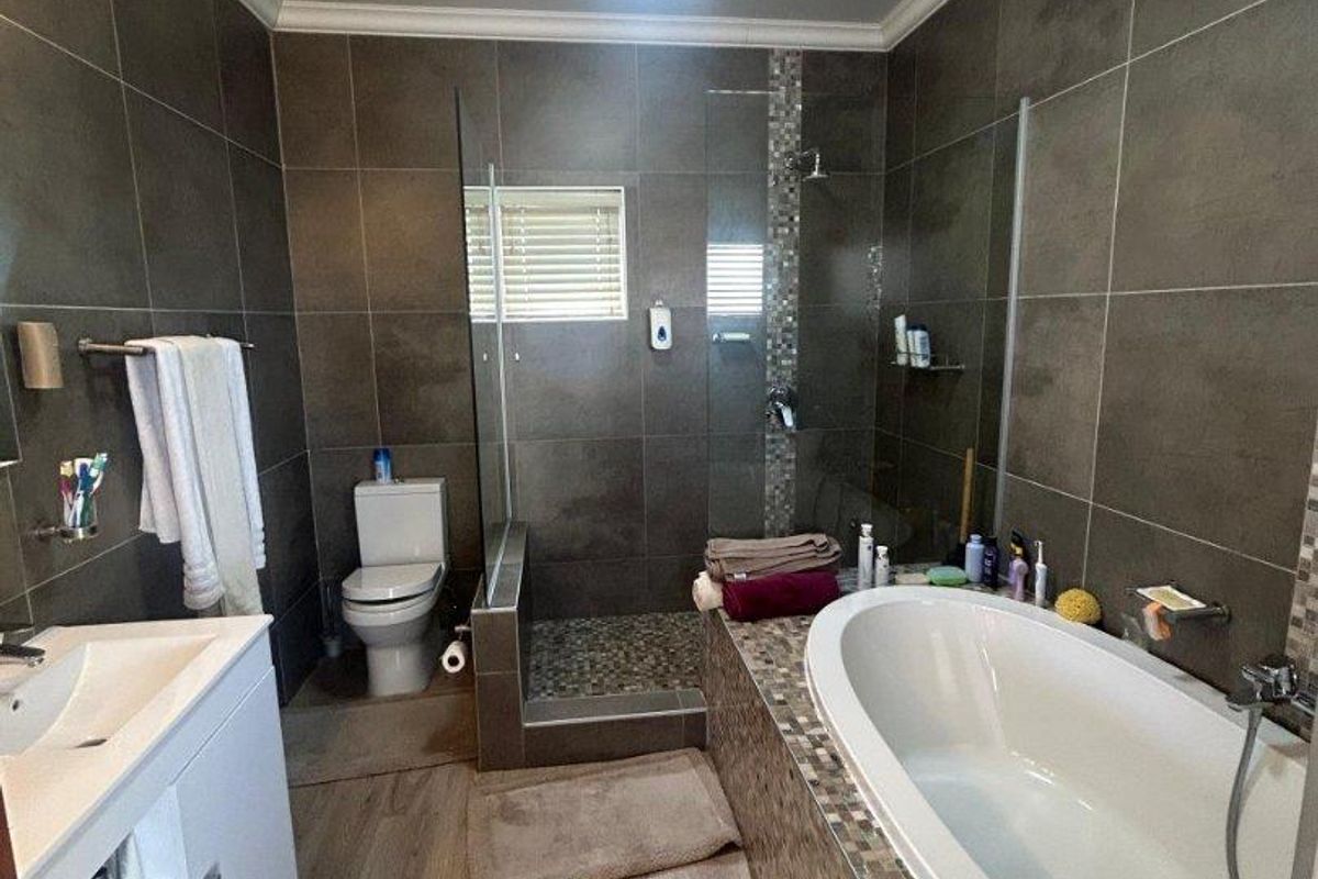 Modern bathroom featuring a tiled walk-in shower, a built-in bathtub with mosaic detailing, a vanity unit, and a toilet.