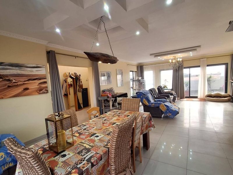 Spacious open-plan living and dining area featuring a decorative coffered ceiling, recessed lighting, and large sliding glass doors leading to the exterior.