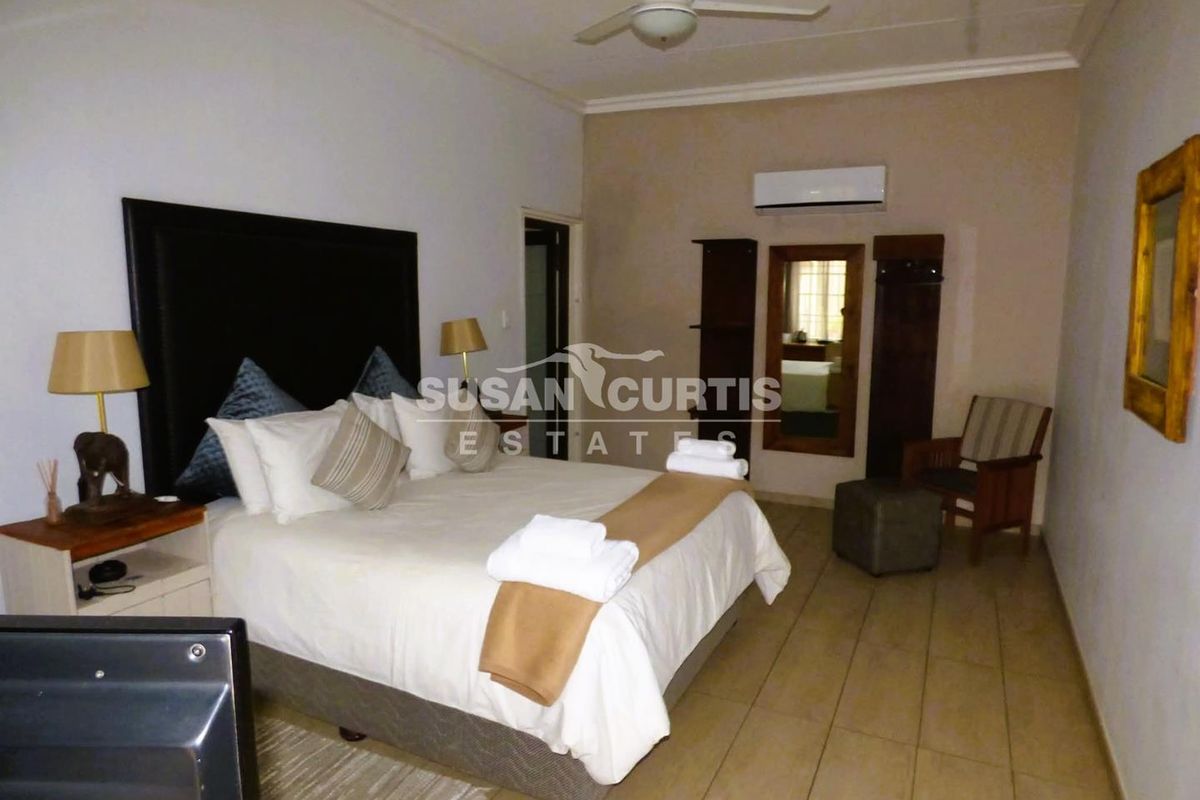 A comfortable bedroom featuring tiled flooring, a ceiling fan, and a wall-mounted air conditioning unit.