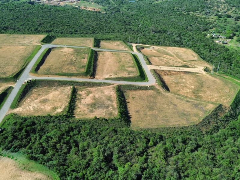 Aerial view of a developed industrial land site featuring multiple terraced plots with established paved access roads and surrounding natural vegetation.