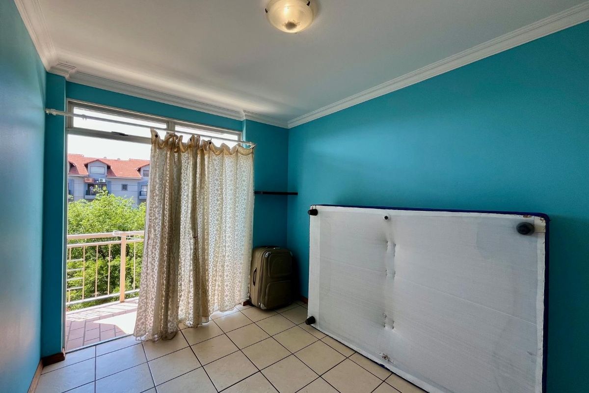A bedroom featuring tiled flooring, crown molding, and direct access to a private balcony through a sliding glass door.