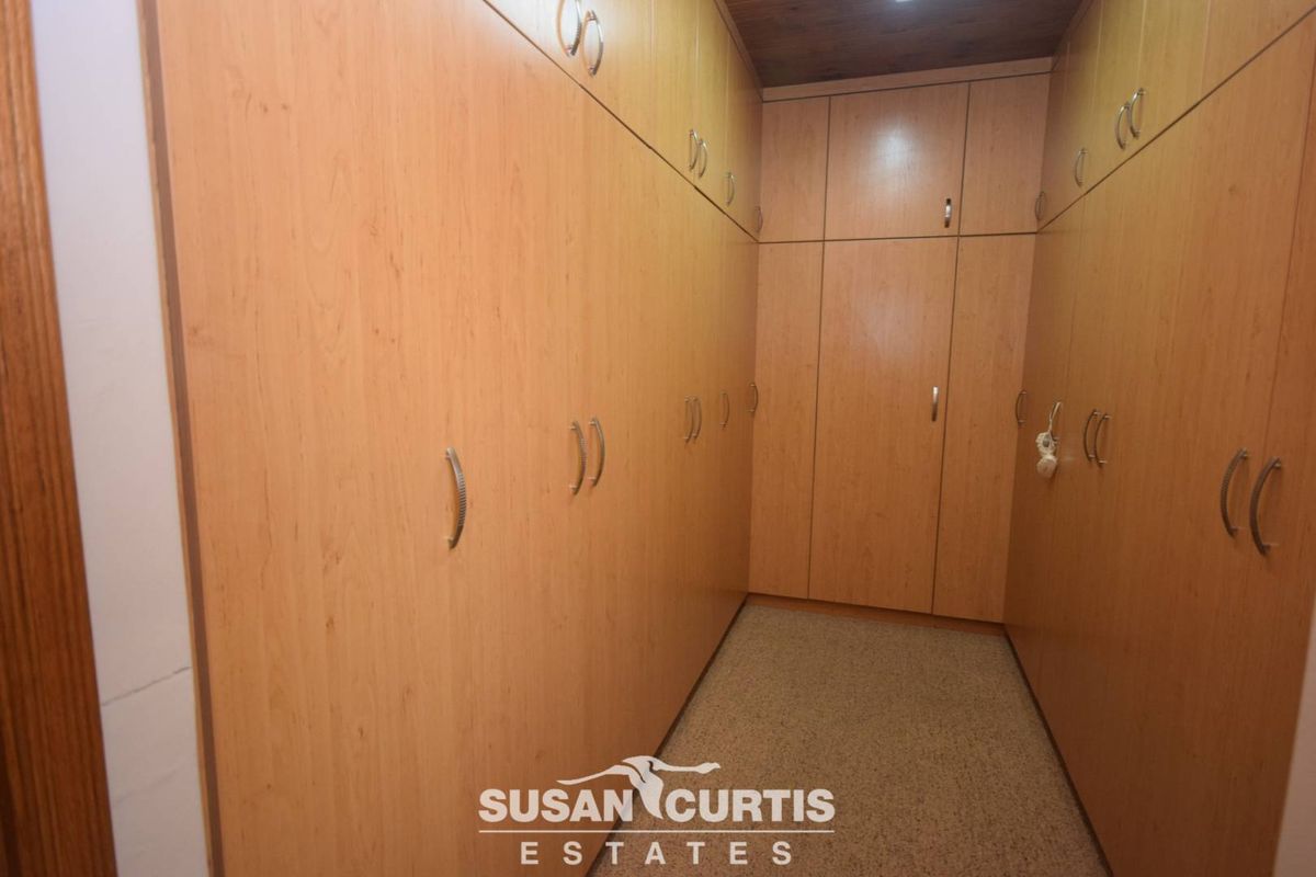 A walk-in dressing room featuring extensive floor-to-ceiling built-in wooden cabinetry providing ample storage space.