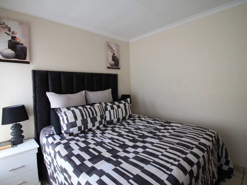 A neutrally painted bedroom featuring tiled flooring and decorative coving, providing a clean and functional sleeping space.