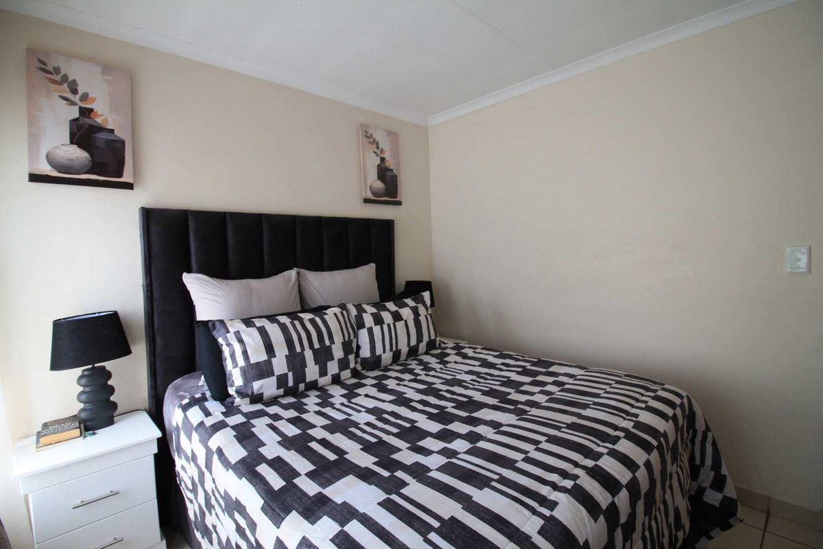 A neutrally painted bedroom featuring tiled flooring and decorative coving, providing a clean and functional sleeping space.