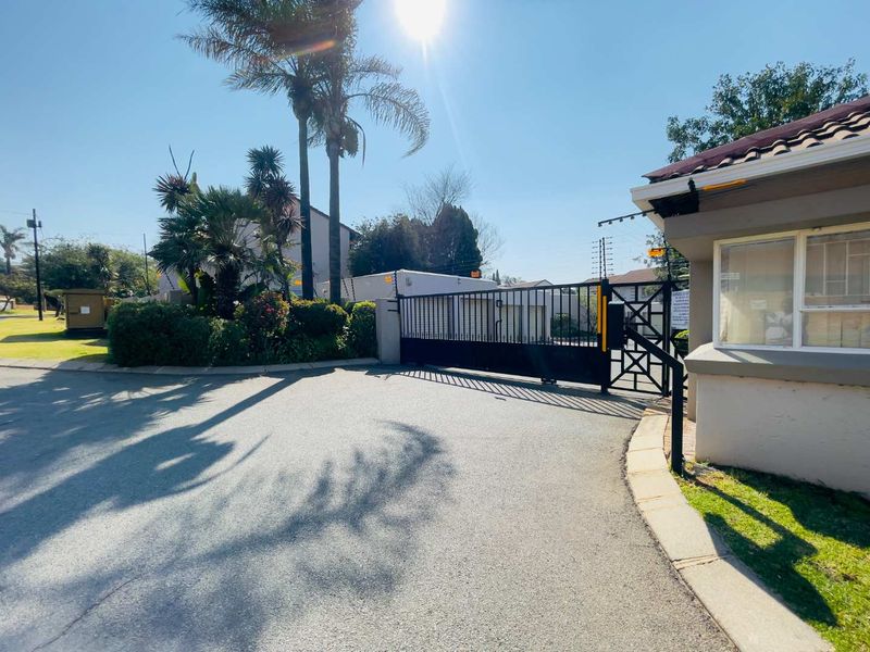 The entrance to the apartment complex features a secure electric gate, perimeter fencing, and a dedicated guard house for controlled access.