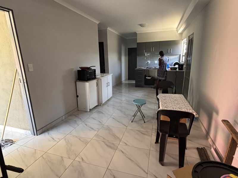 Open-plan living and kitchen area featuring marble-look floor tiles and built-in cabinetry, providing a functional space for cooking and dining.