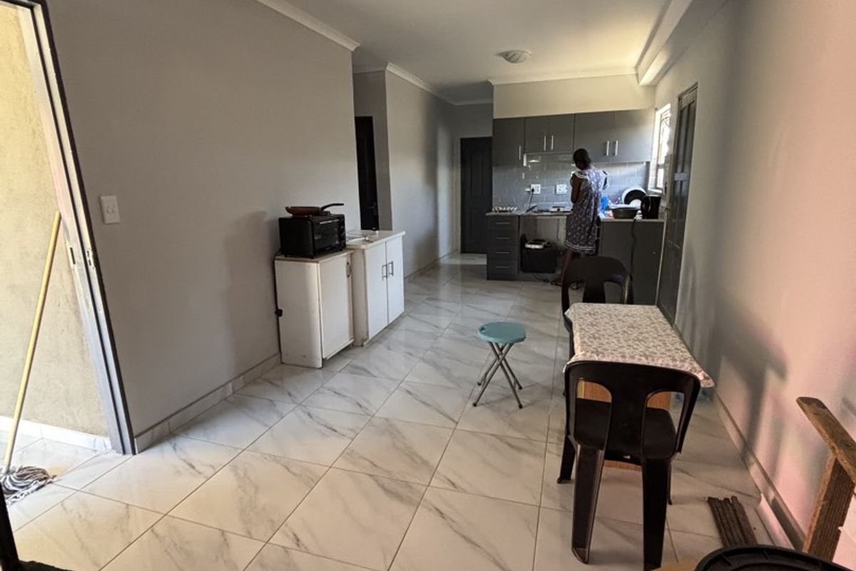 Open-plan living and kitchen area featuring marble-look floor tiles and built-in cabinetry, providing a functional space for cooking and dining.
