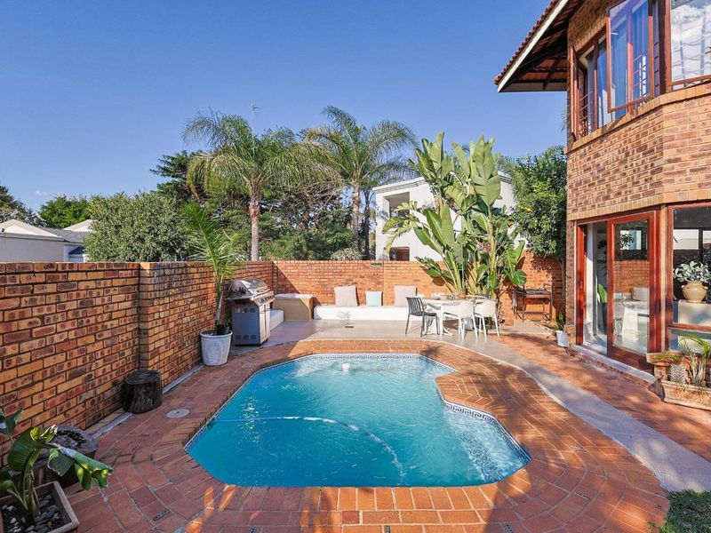 A private outdoor pool area featuring brick paving, a surrounding brick boundary wall, and direct access to the home through sliding glass doors.