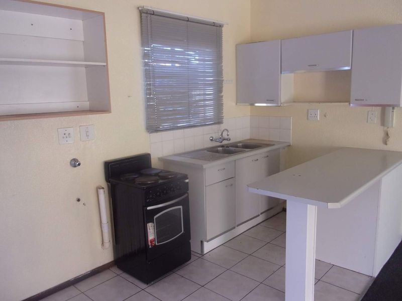 A functional kitchen featuring built-in cabinetry, a breakfast bar, tiled flooring, and a stainless steel sink, offering a blank canvas for modern updates.