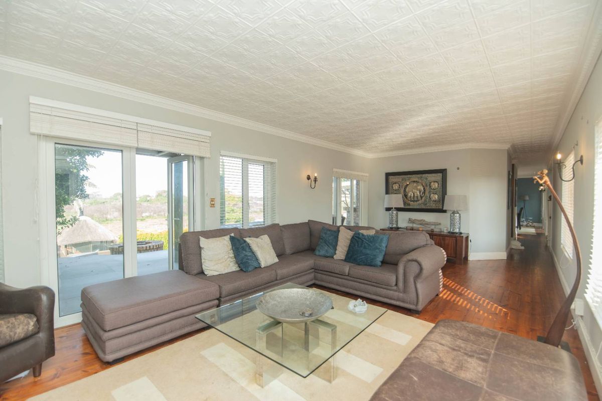 Spacious living room featuring polished timber flooring, a decorative pressed metal ceiling, and large sliding glass doors providing access to the outdoor patio area.