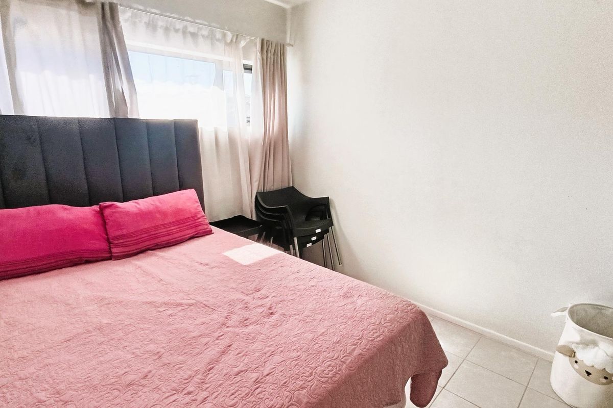A bedroom featuring tiled flooring and a window with curtains, providing a functional space for rest.