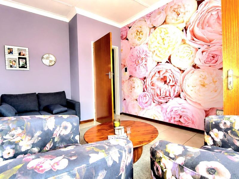 A living room featuring tiled flooring, coving, and a prominent floral feature wall, providing a distinct aesthetic space.