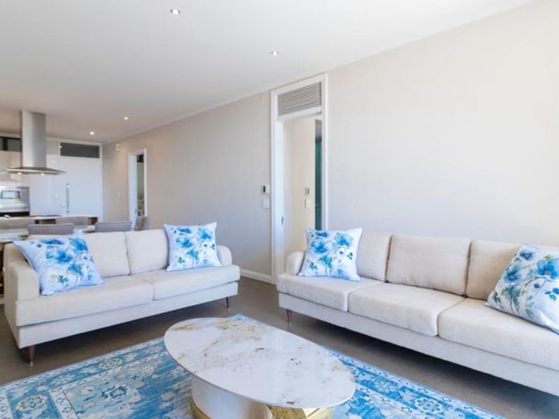 Modern open-plan living area featuring tiled floors, recessed lighting, and a sleek kitchen with integrated extractor fan.