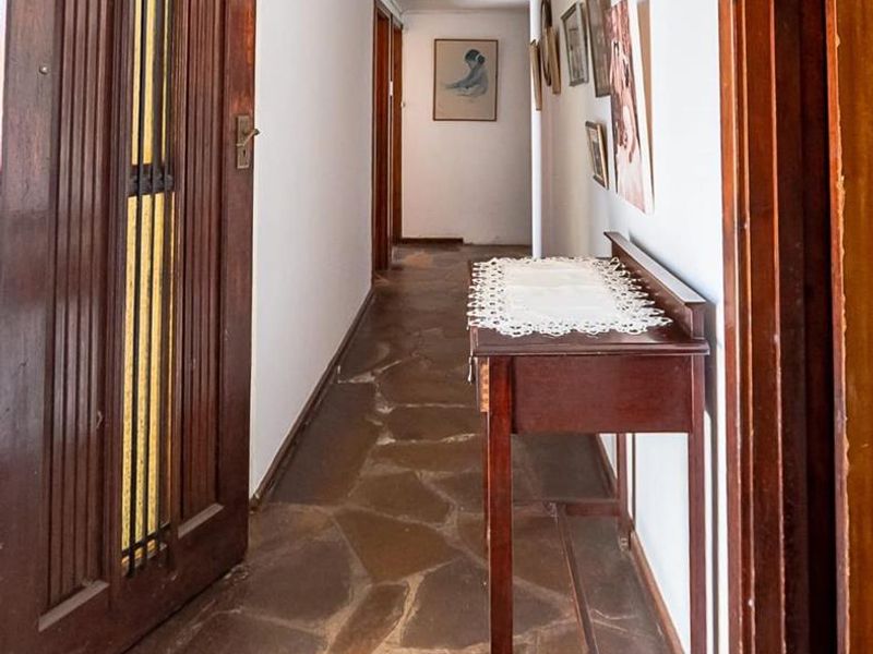 A long hallway featuring rustic flagstone flooring and solid timber door frames, providing access to various rooms within the home.