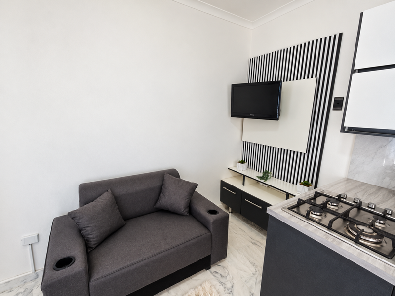 Compact open-plan living area featuring a modern gas hob, sleek built-in cabinetry, and stylish marble-look floor tiles.