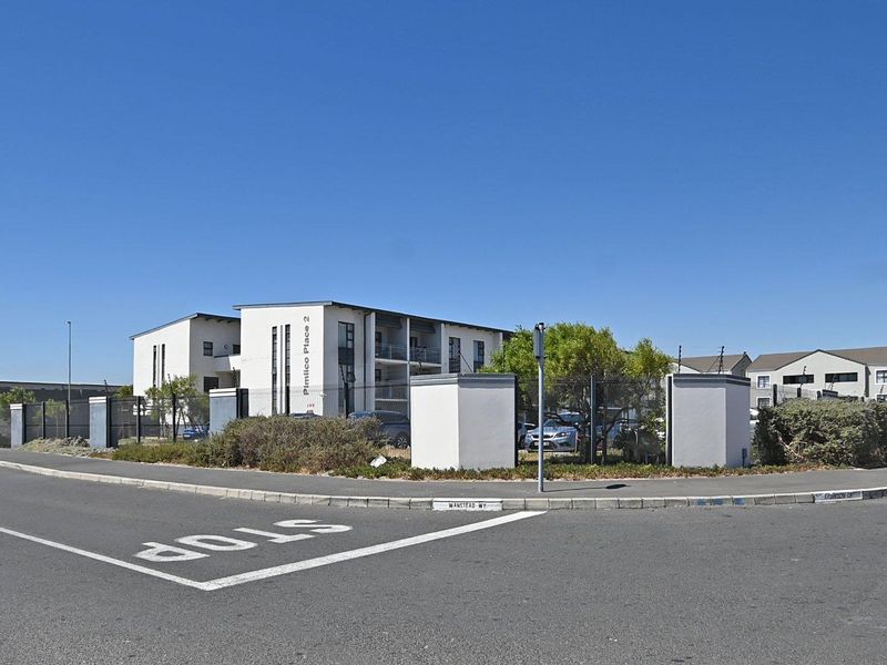 Street view of the Pimlico Place 2 apartment complex, featuring modern building architecture, secure perimeter fencing, and gated access from the road.