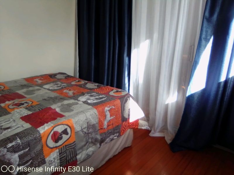 A bedroom featuring hardwood flooring and a sliding glass door with curtains, providing access to an outdoor area.