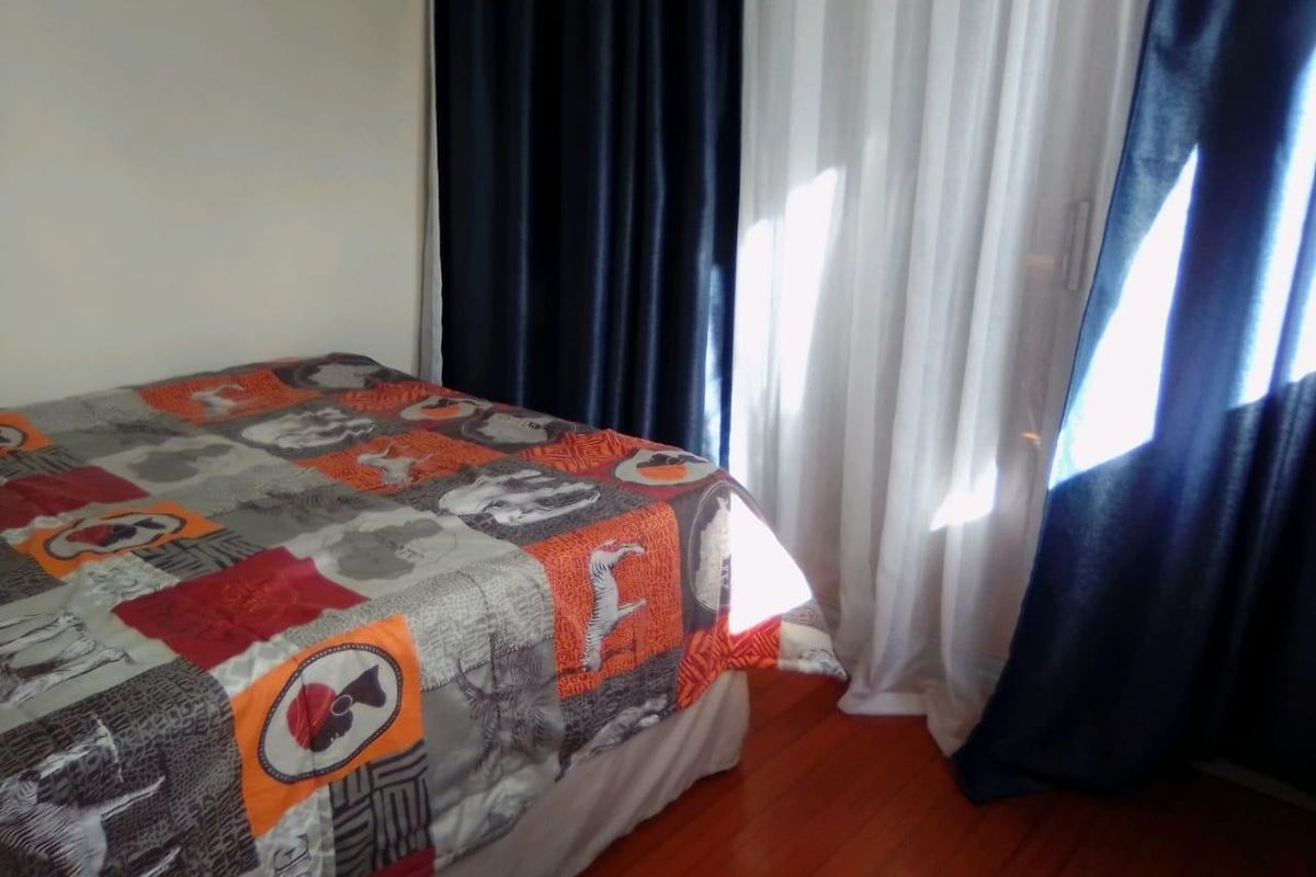 A bedroom featuring hardwood flooring and a sliding glass door with curtains, providing access to an outdoor area.