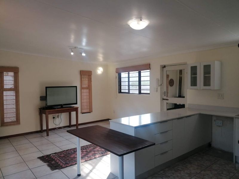 Open-plan living and kitchen area featuring tiled flooring, modern cabinetry, and stone countertops, providing a functional and versatile space for daily living.