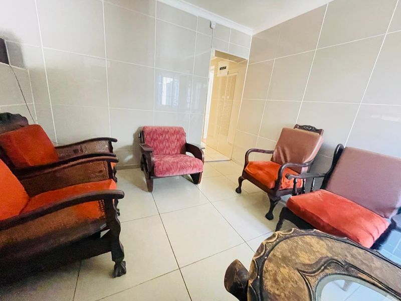 A living area featuring large format wall and floor tiles with a coved ceiling, providing a neutral base for interior updates.